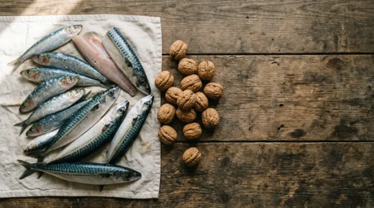 Composición de pescados azules frescos y frutos secos sobre mesa de madera con luz natural mediterránea