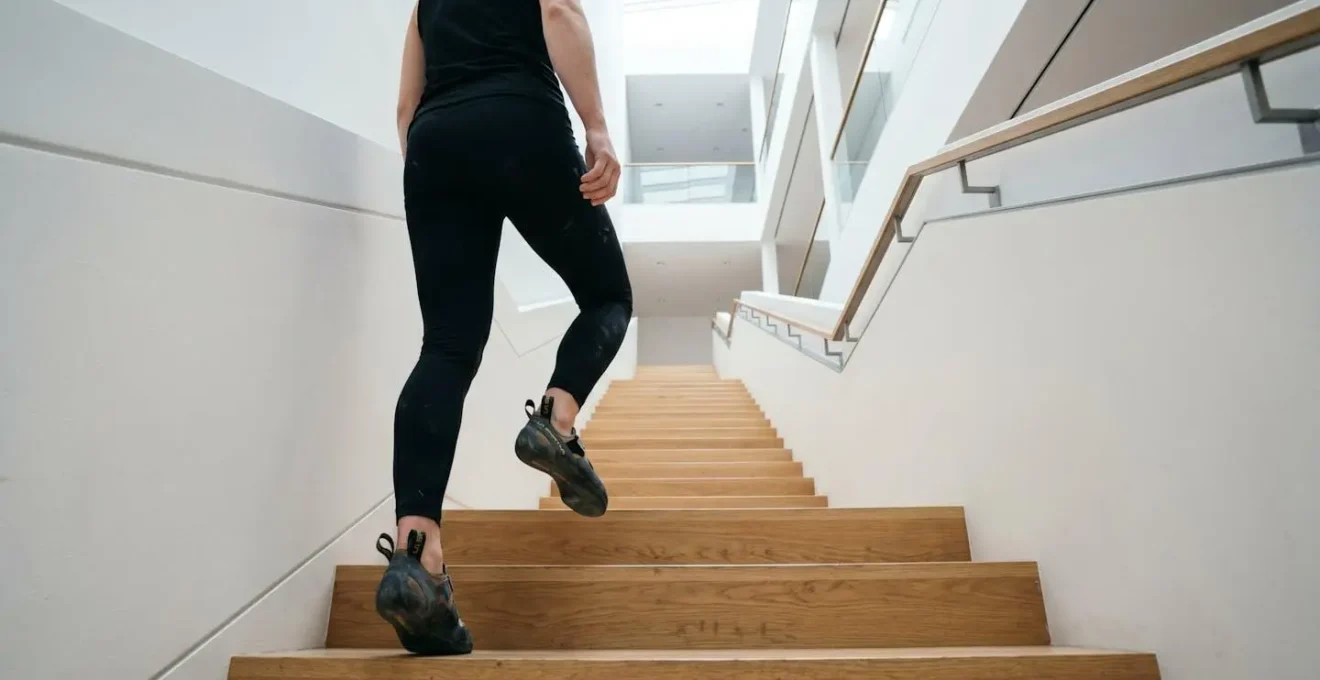 Vista lateral de persona subiendo escaleras con determinación, mostrando esfuerzo controlado