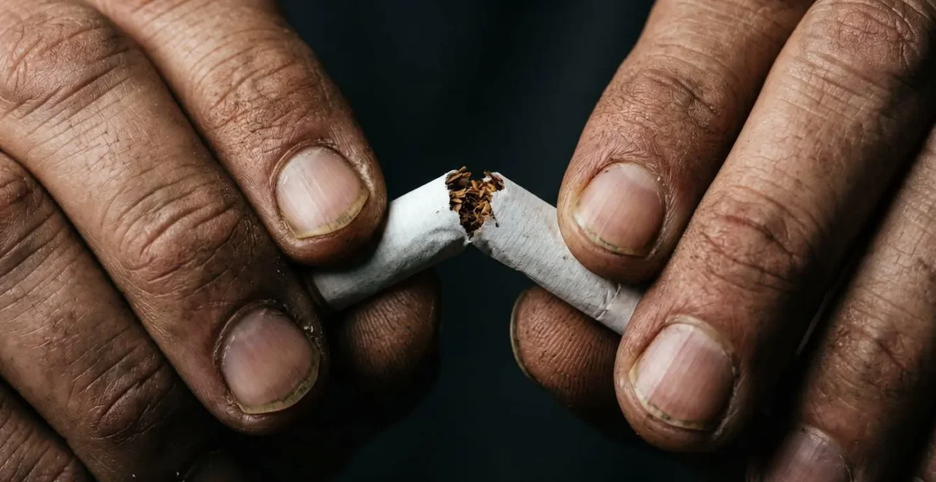 Manos sosteniendo simbólicamente el último cigarrillo antes de desecharlo